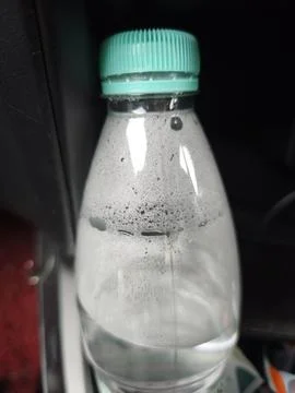 Cold water bottle with teal cap and condensation in car cup holder. Stock Photos