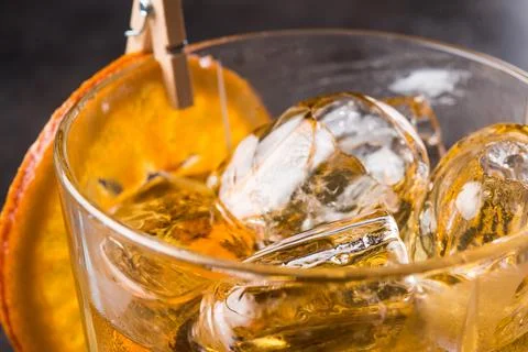 Cold whiskey or scotch with ice and orange slice Stock Photos