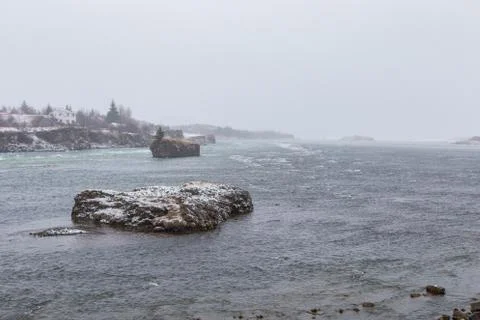 Cold winter blizzard causes heavy snow fall on river rocks Stock Photos