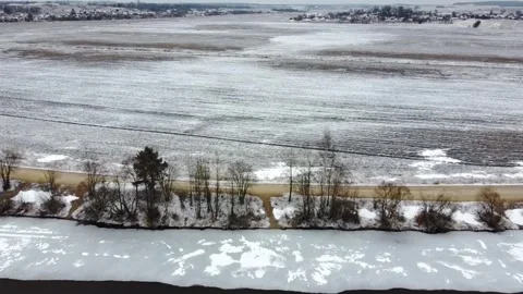 Cold winter landscape with snow on river and fields near small town during cloud Stock Footage 329360306