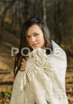Cold woman wraps blanket over herself while standing in color autumn park Stock Photos