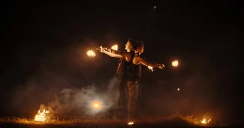 Coll fire show artists having a performance in the dark, swinging fire pieces Video stock 100994108