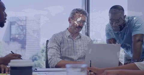 Collaborating colleagues analyzing documents around office desk, with laptop and Stock Photos