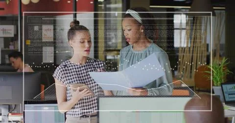 Collaborating coworkers reviewing code overlays on monitors in office with Stock Photos