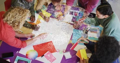 Collaborating design team leaning around table in studio, passing color wheel Stock Photos