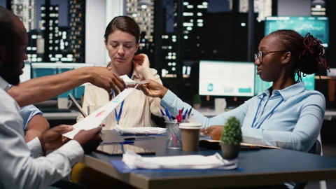 Collaborating, multiethnic team of office clerks completing spreadsheets Stock Footage 334043640