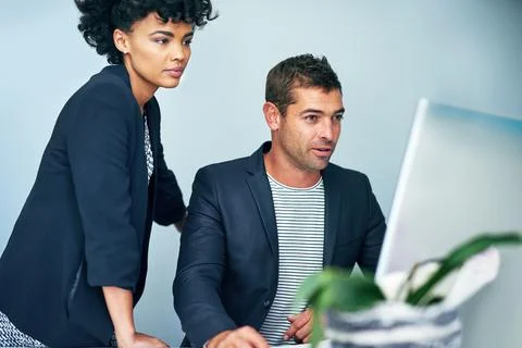 Collaborating on problem solving. two coworkers working together at a computer Stockfoto's