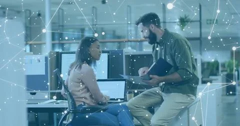 Collaborating software professionals reviewing code at open-plan office desk, Foto stock