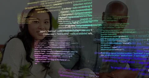 Collaborating software team leaning around tech desk, laptop coffee-cup plant Foto stock