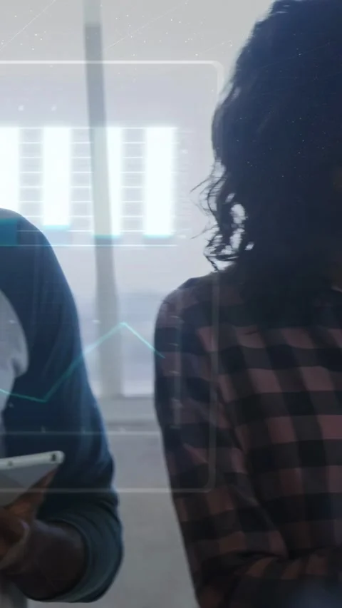 Collaborating team in denim, plaid and raglan tees, tapping tablets by window, Stock Footage 332985023