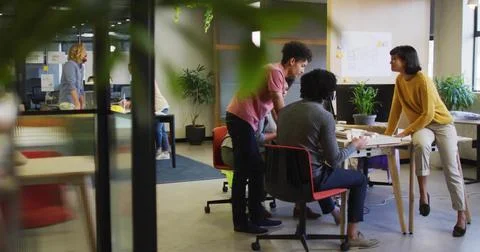 Collaborating team studying architectural plans around table in modern office, Stock Photos
