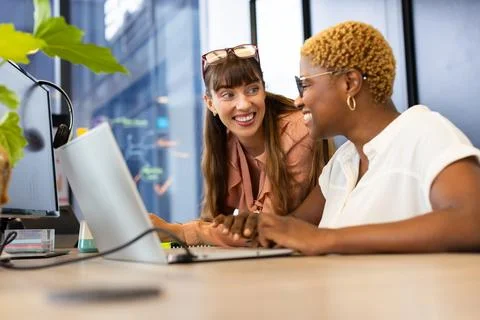 Collaborating at work, two women using laptop and discussing project in office 스톡 사진