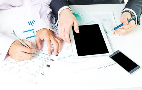 Collaboration among professionals using digital devices and documents at a Stock Photos