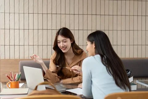 Collaboration and Creativity. Two students share ideas and knowledge while using Stock Photos