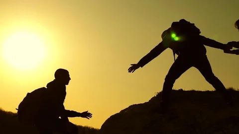 Collaboration climbers travelers at sunset. Silhouettes of men climbing to the Stock Footage