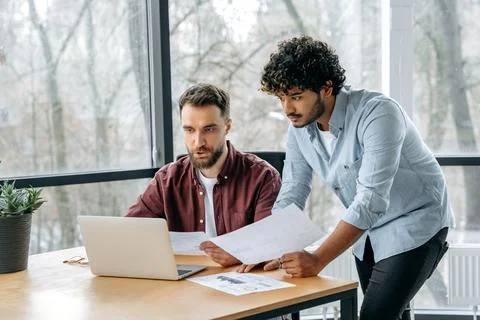 Collaboration concept. Focused successful multiracial male businesspeople work Stock Photos