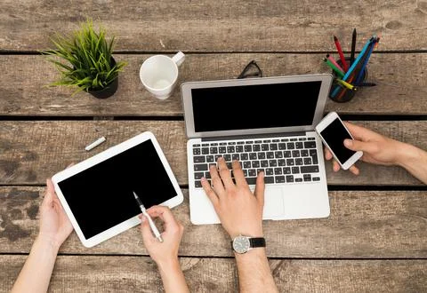 Collaboration at a rustic wooden table with digital devices during a Stock Photos