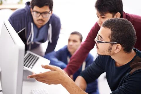 Collaborative coding. Shot of a group of colleagues working together with a c Stock Photos