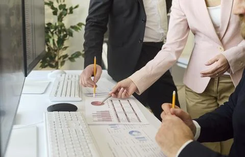Collaborative office meeting reviewing data reports and graphs on desktop Stock Photos