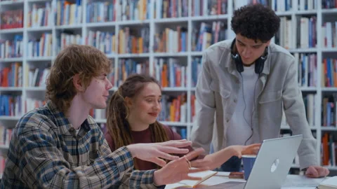 Collaborative Team of College Students Sharing Ideas Around a Library Table 스톡 동영상 335131458