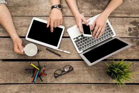 Collaborative workspace with technology and drinks at a wooden table during Stock Photos