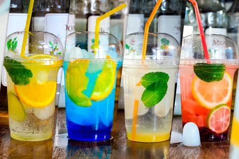 A collage of several refreshing drinks with ice in disposable glasses. Stock Photos