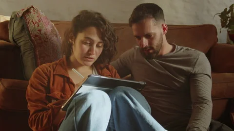 Collage students studying together from an iPad in the living room Video stock 160244598