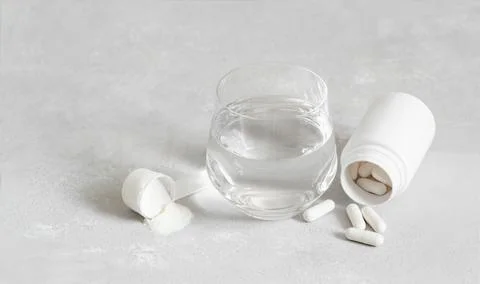 Collagen on a gray background. Collagen powder or protein, pills and a glass  Stock Photos