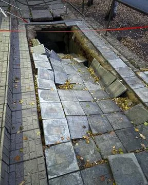 Collapse of the sidewalk from tiles into a deep pit. The concept of infrast.. Stock Photos