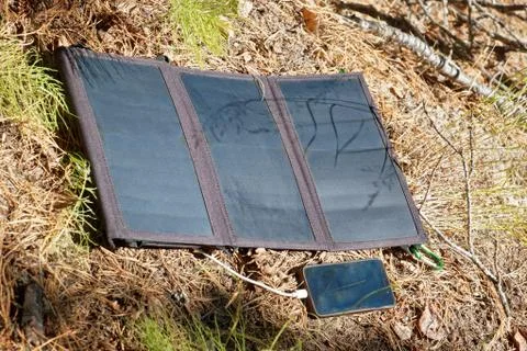 Collapsible solar panel charges a smartphone Stock Photos