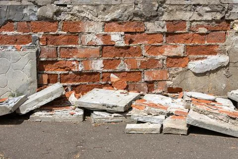 Collapsing facade of a brick house with a falling off decorative coating Stock Photos