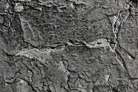 Collapsing layer of black paint on the concrete surface. Abstract background. Stock Photos