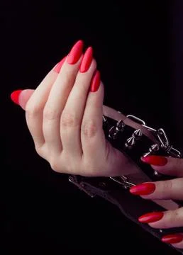Collar in hand with red painted nails studio shot at black background. Stock Photos