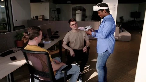 Colleague helps put on vr headset. Testing metaverse world, touching virtual Stock Footage 235621971