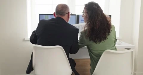 Colleagues analyzing financial data on computer screens in a bright office Stock Footage 330686862