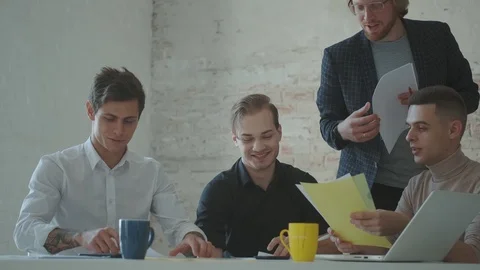 Colleagues are sitting at the table in the office. the group leader is talking Stock Footage 119110017