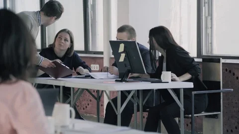 Colleagues are sitting at a table in the office with a computer and discussing Stock Footage 124663092
