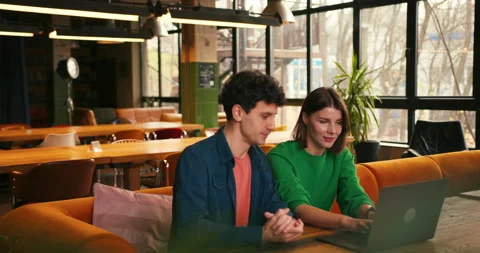 Colleagues brainstorming new ideas using laptop in modern cafe Stock Footage 322520680