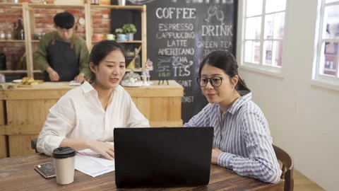 Colleagues at cafe table talking on laptop 動画素材 140152517