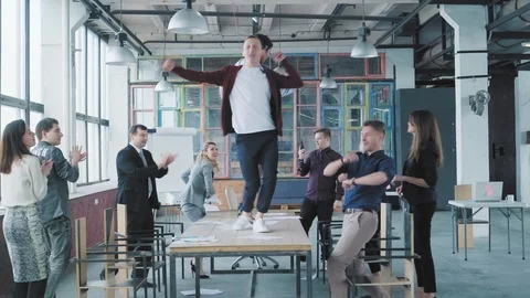 Colleagues celebrate the end of the work week, have fun dancing on the table and Stock Footage 108367797