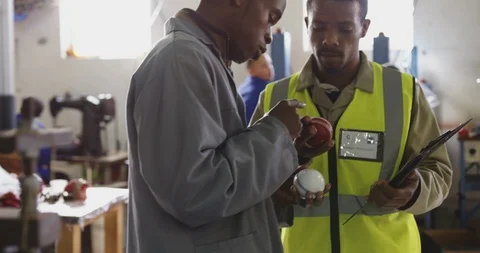 Colleagues checking quality cricket ball in factory Stock Footage 124590341