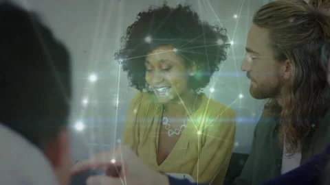 Colleagues collaborating around office table, integrating tech graphics with Stock Footage 307443835