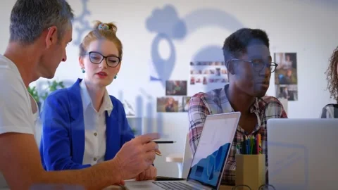 Colleagues collaborating as colleague entering left pointing at laptop, tapping Stock Footage 334111427