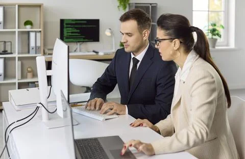 Colleagues collaborating at desktop computers in modern office, coding tasks Stock Photos