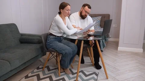 Colleagues collaborating on laptop: analyzing documents at shared workspace Stock Footage 317442724