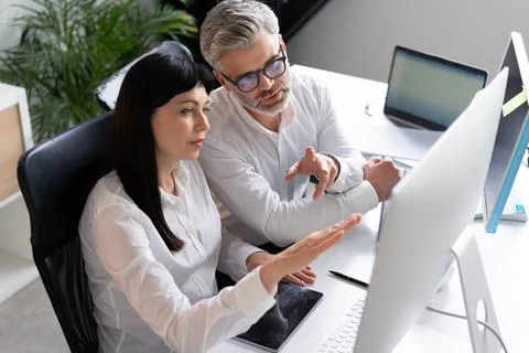 Colleagues Collaborating at Office Desk With Computer and Tablet Stock Photos