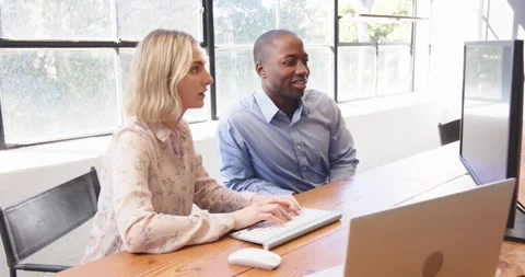 Colleagues collaborating at office desk, using computer and smiling during Stock Footage 346285378