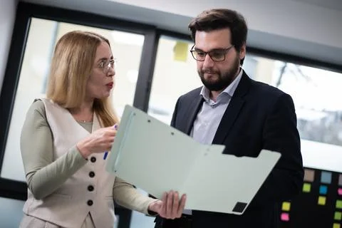 Colleagues collaborating on a project in a modern office space, analyzing data Stockfoto's