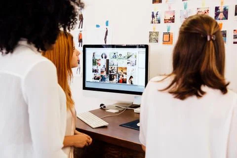 Colleagues in creative studio having discussion, using computer 스톡 사진