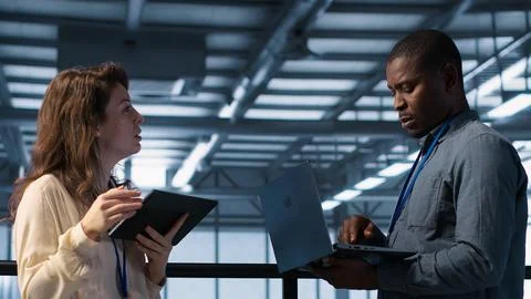 Colleagues in data center workplace use laptop to calibrate energy usage Stock Photos